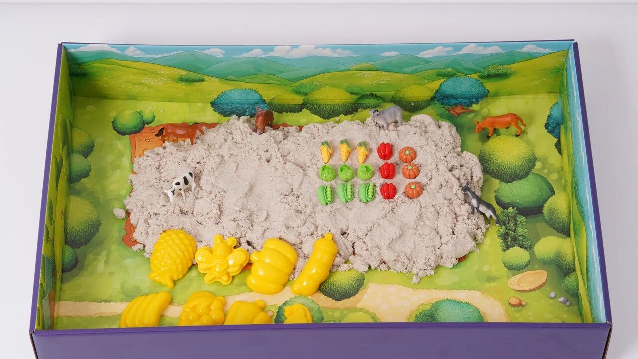 Кинетический песок насыпан горкой на игровом лотке с фигурками животных и жёлтыми формочками