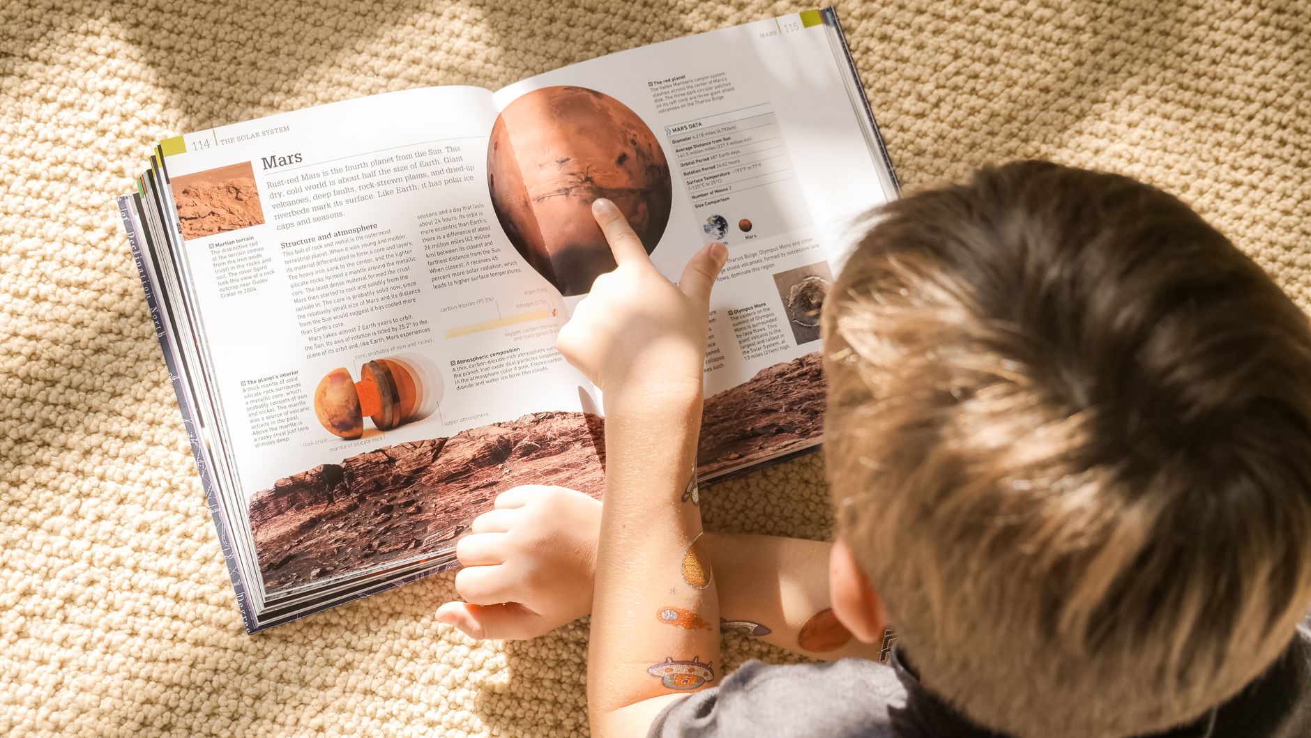 Мальчик разглядывает разворот книги с фотографией Марса